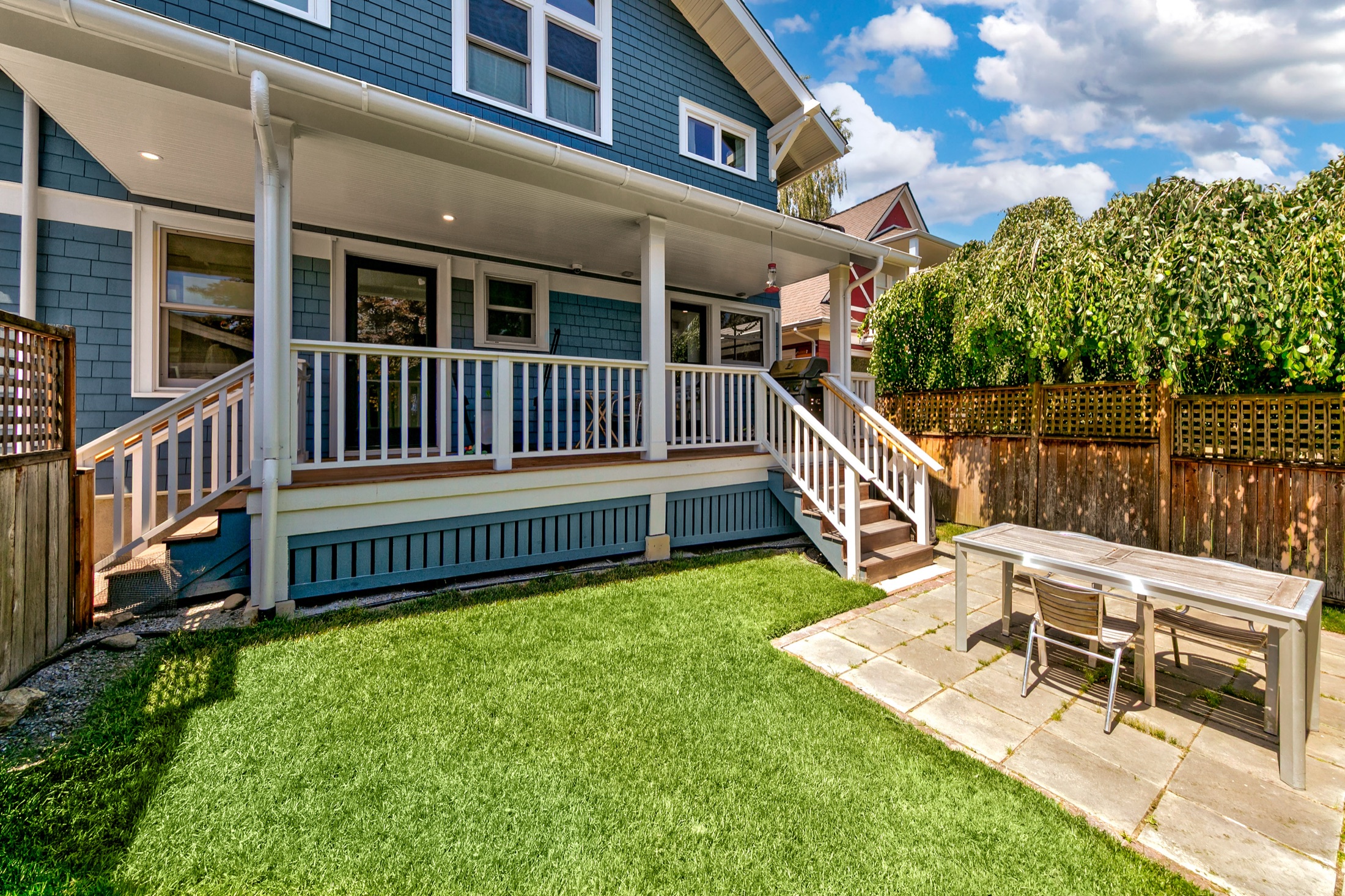 Rear exterior with covered porch, stairs, and lawn