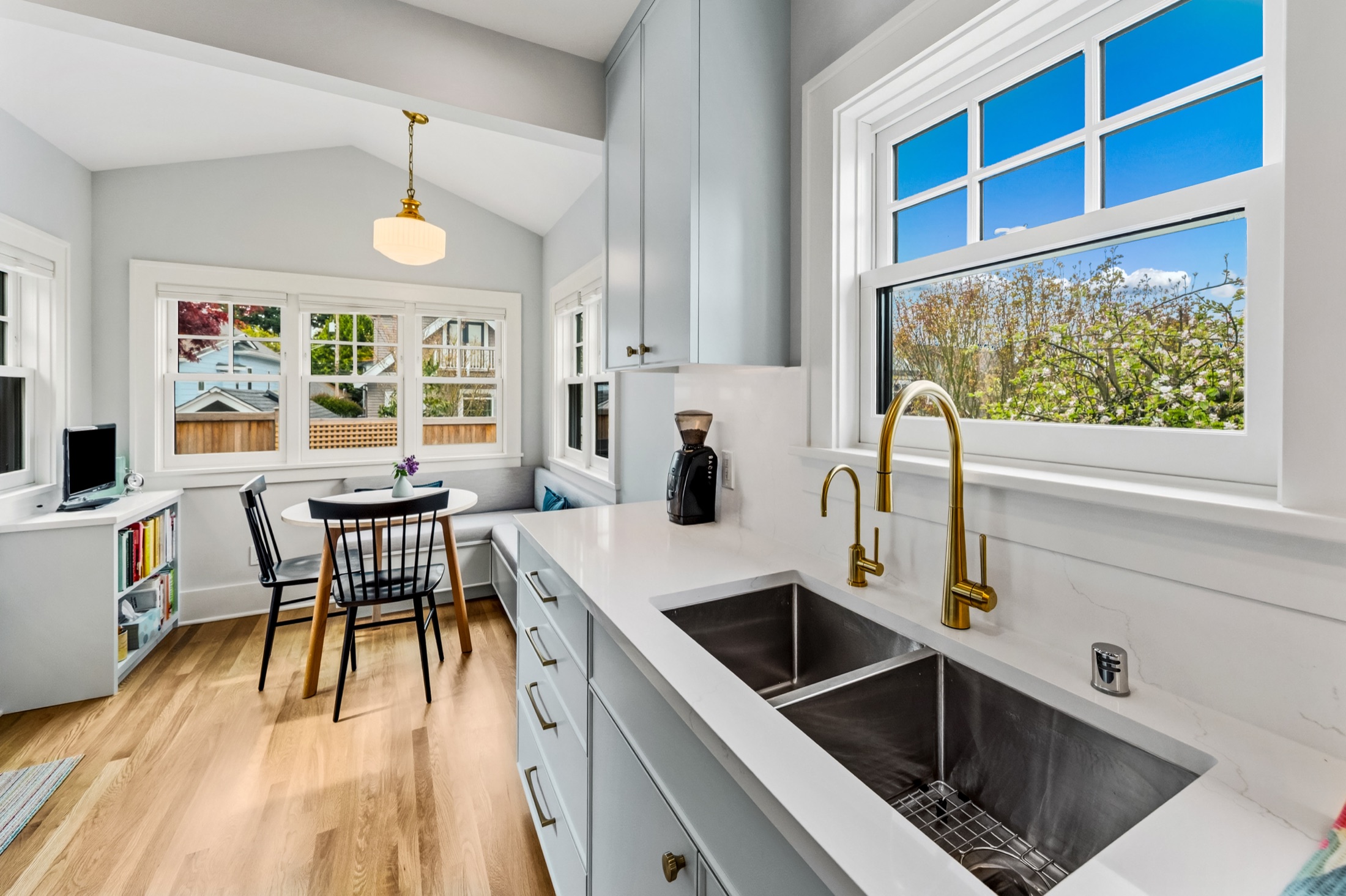 Kitchen sink beneath a wide window with brass faucet