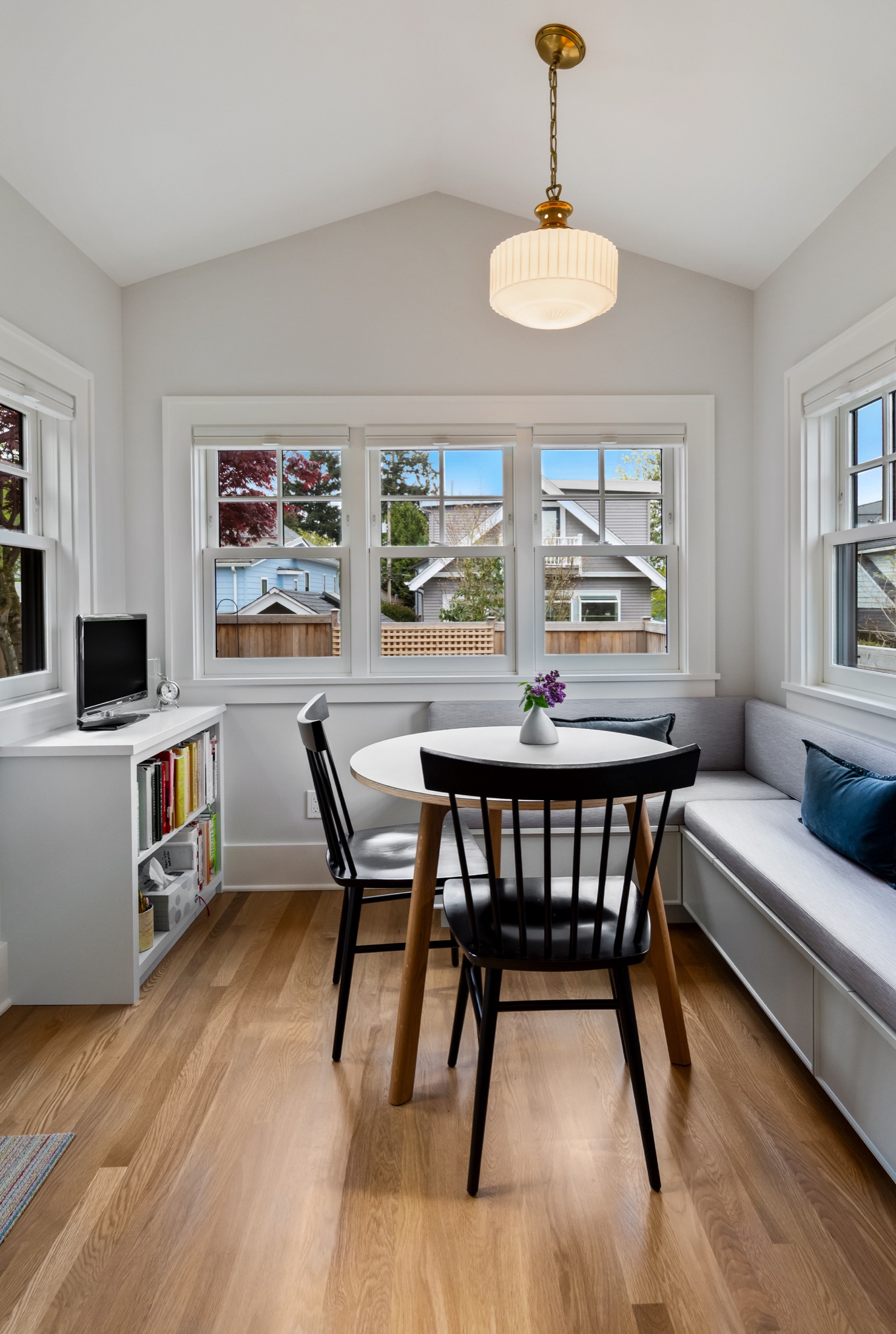 Breakfast nook framed by windows and a globe pendant