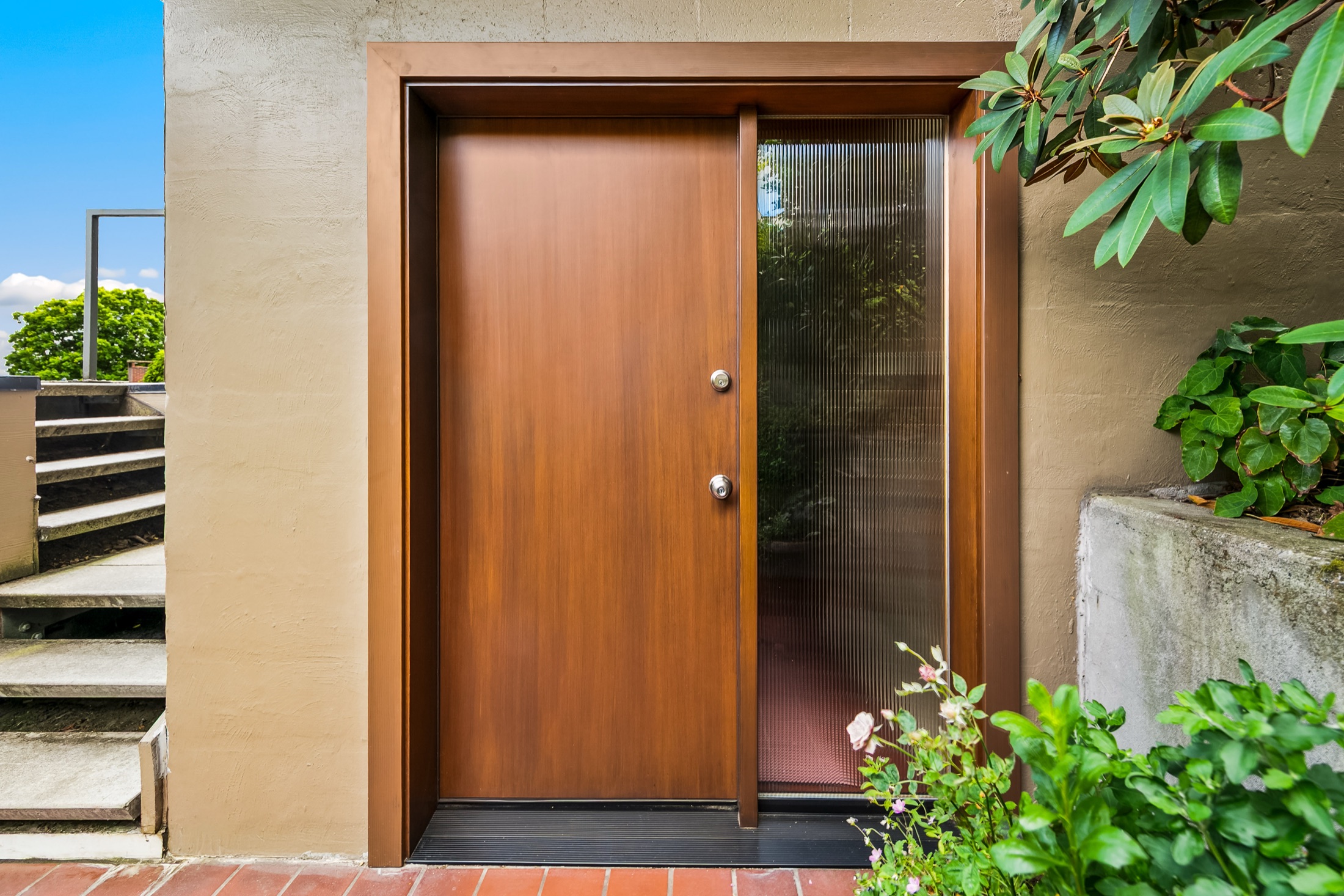 Closed wood front door framed by concrete and landscaping