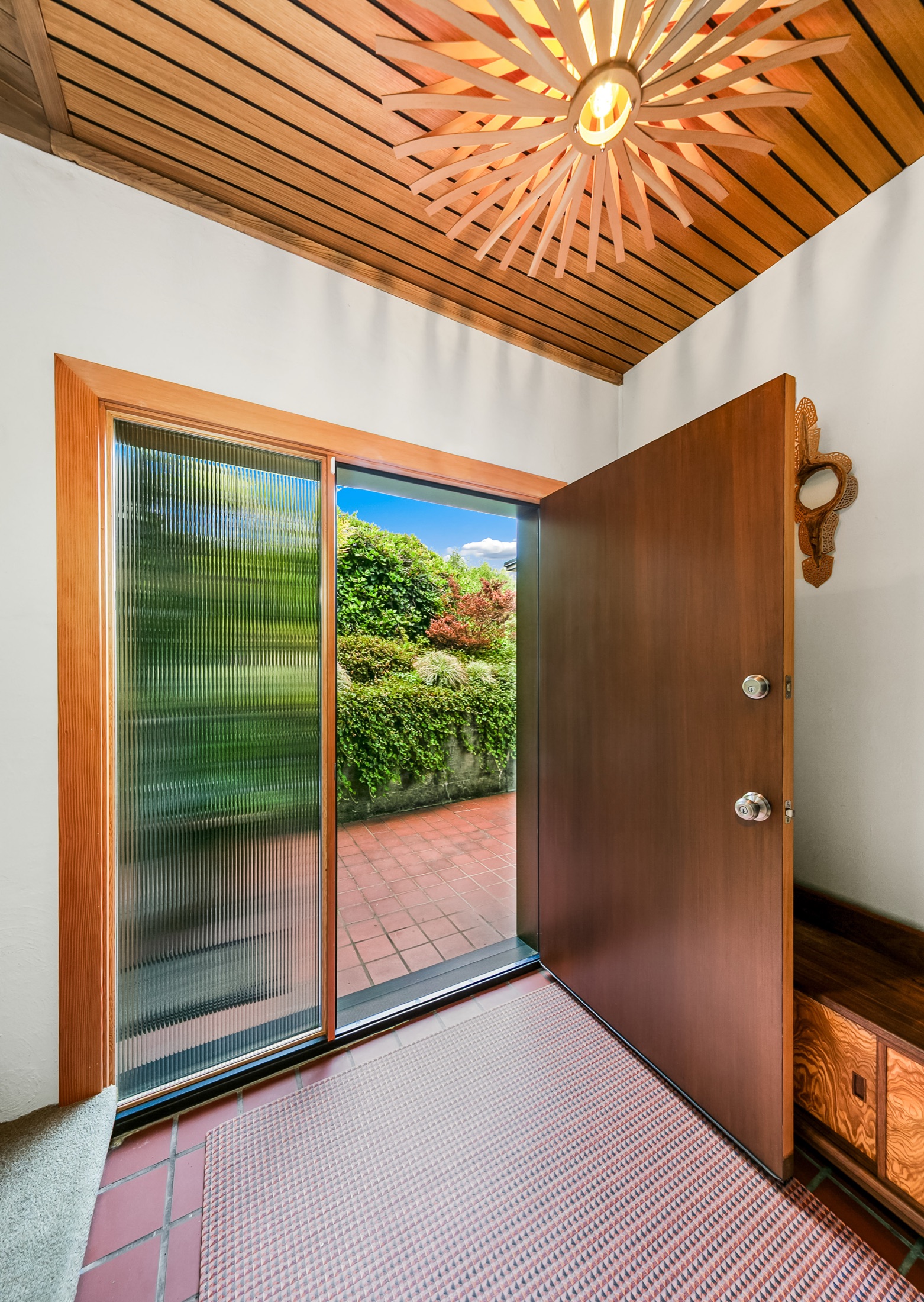 Interior entry with open wood door and slatted ceiling
